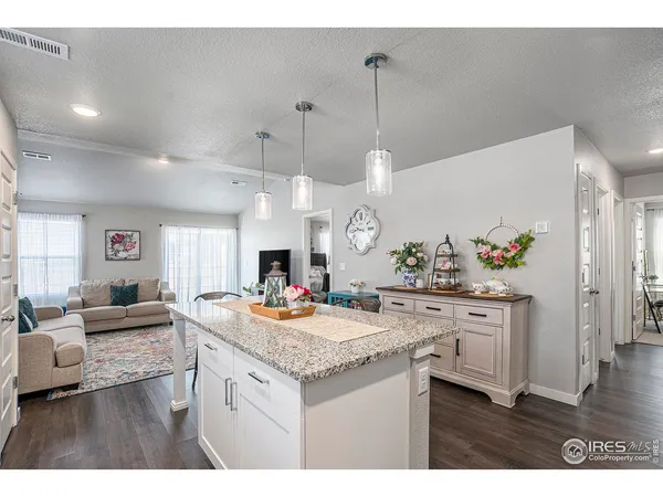 a living room with furniture a wooden floor and kitchen view