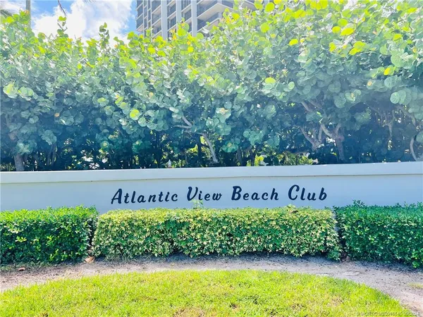 a view of a multi story residential apartment building with a yard and large trees