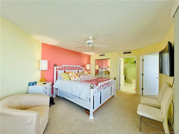 a bedroom with a bed and a flat tv screen on a dresser