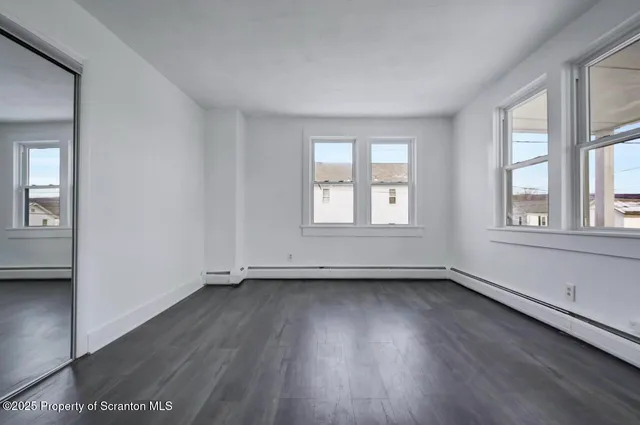 a view of an empty room with wooden floor and window