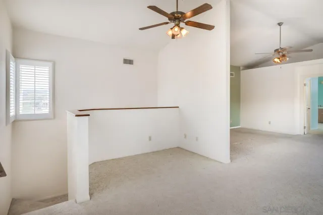 an empty room with windows and fan