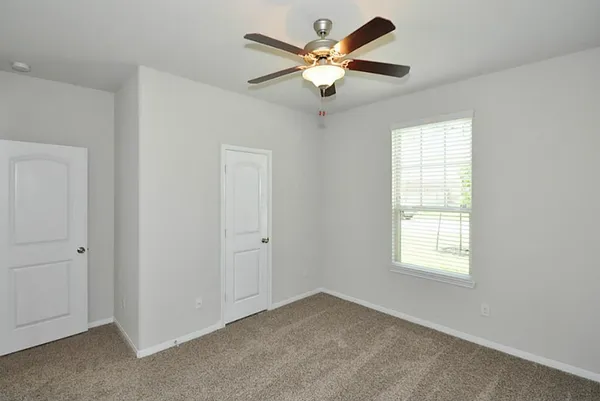 an empty room with windows and ceiling fan