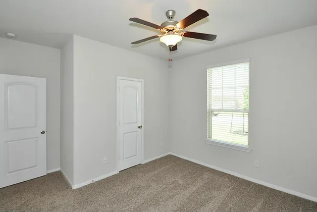 an empty room with windows and ceiling fan