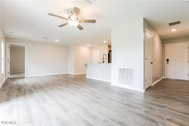 a view of an empty room with wooden floor and a ceiling fan