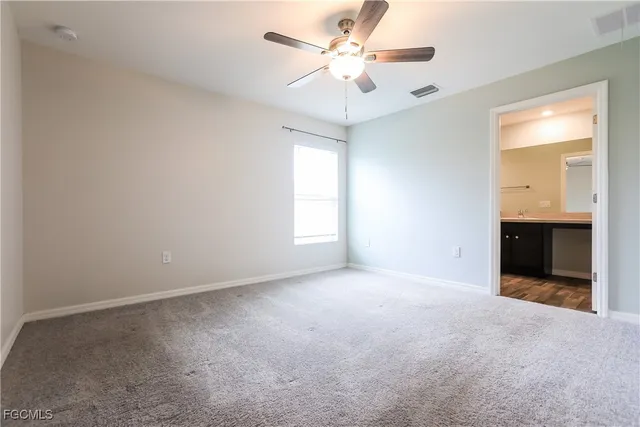an empty room with chandelier fan and windows