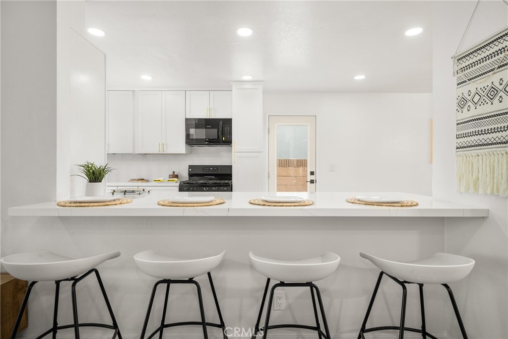 19212 Gunlock Avenue Carson, CA 90746 - Photo 13 of 56 a kitchen with stainless steel appliances kitchen island a table chairs in it and white cabinets
