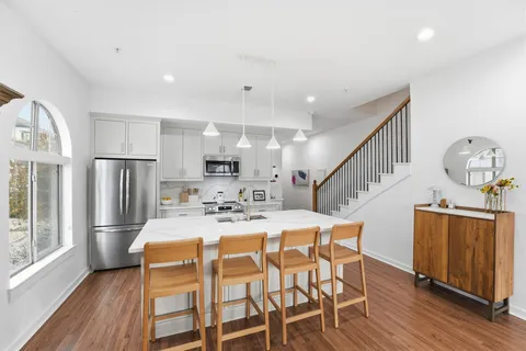 a kitchen with stainless steel appliances kitchen island granite countertop a kitchen island hardwood floor and a window