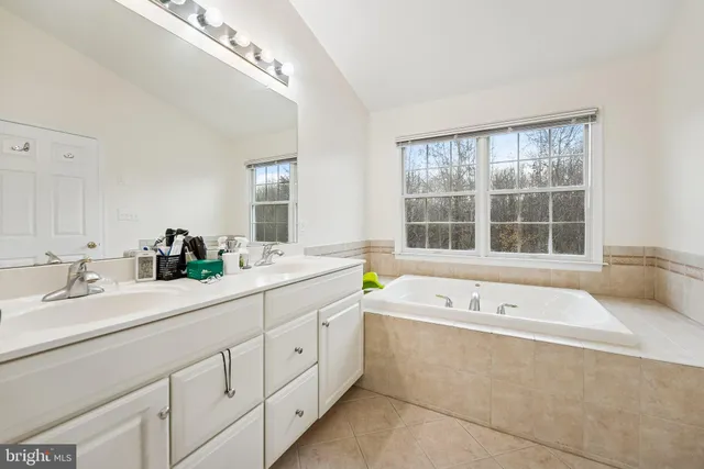 a spacious bathroom with a tub a double vanity sink and large window