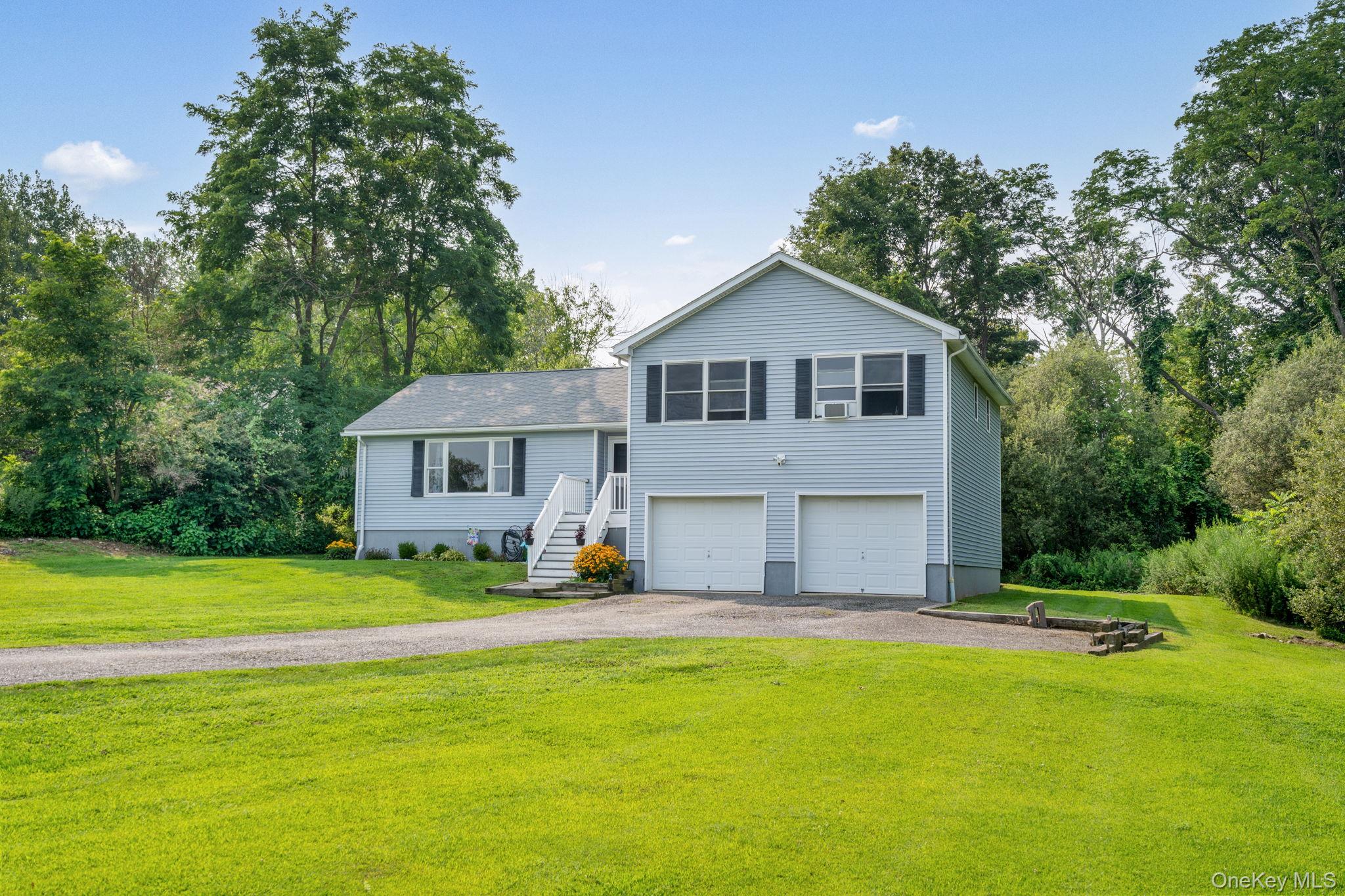 23 Countryview Road Millerton, NY 12546 - Photo 1 of 1 Split level home with driveway, view of wooded area, a front yard, and a garage