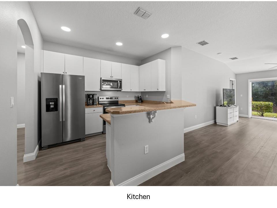 8516 Corinthian Way New Port Richey, FL 34654 - Photo 2 of 24 a kitchen with refrigerator cabinets and wooden floor