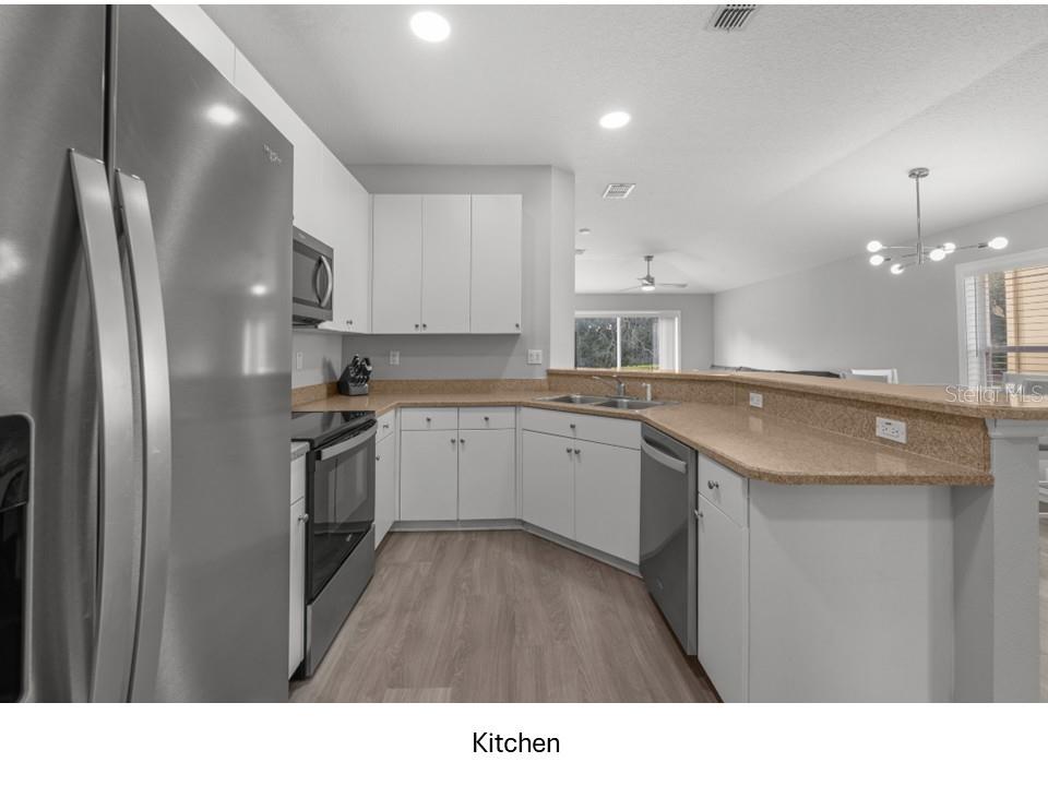 8516 Corinthian Way New Port Richey, FL 34654 - Photo 3 of 24 a kitchen with white cabinets appliances and sink