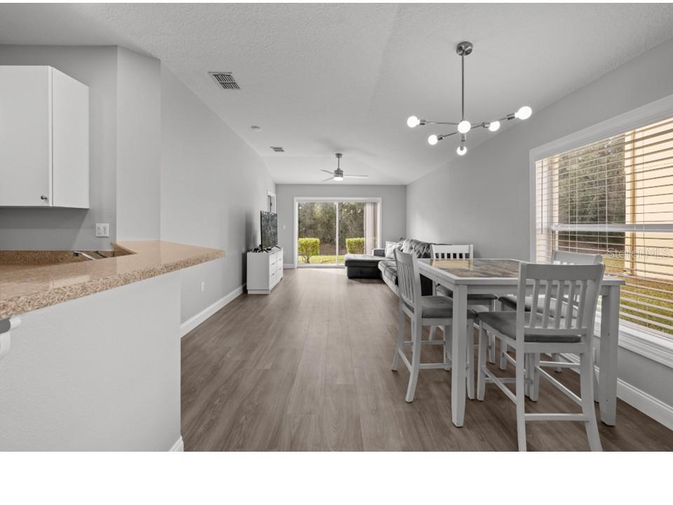 8516 Corinthian Way New Port Richey, FL 34654 - Photo 4 of 24 a living room with furniture dining table and a chandelier