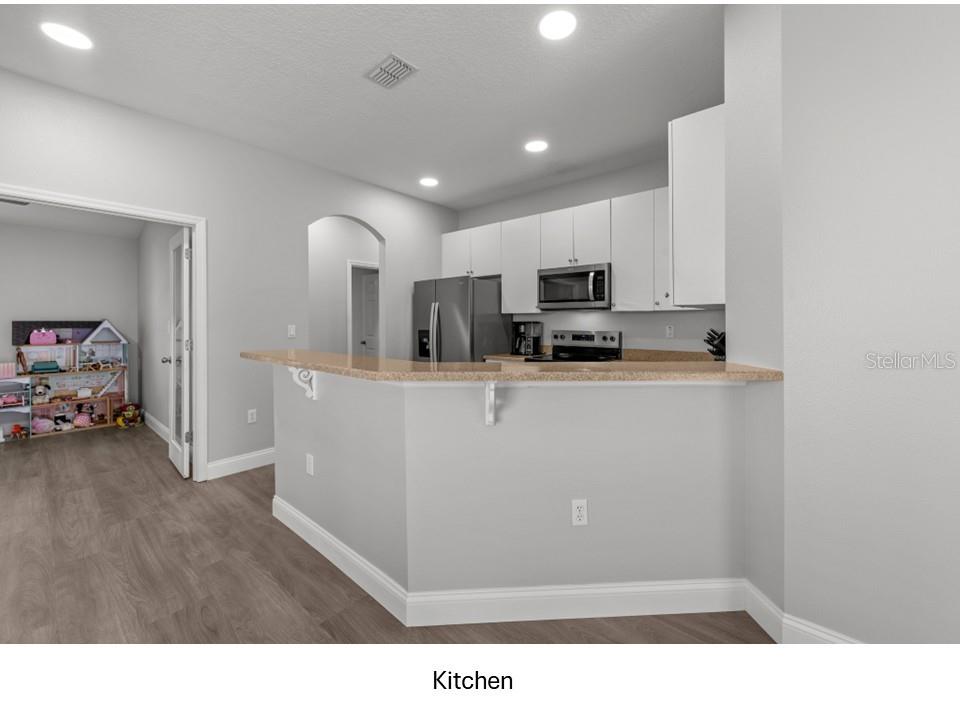 8516 Corinthian Way New Port Richey, FL 34654 - Photo 7 of 24 a living room with stainless steel appliances kitchen island granite countertop a sink a stove top oven a dining table and chairs