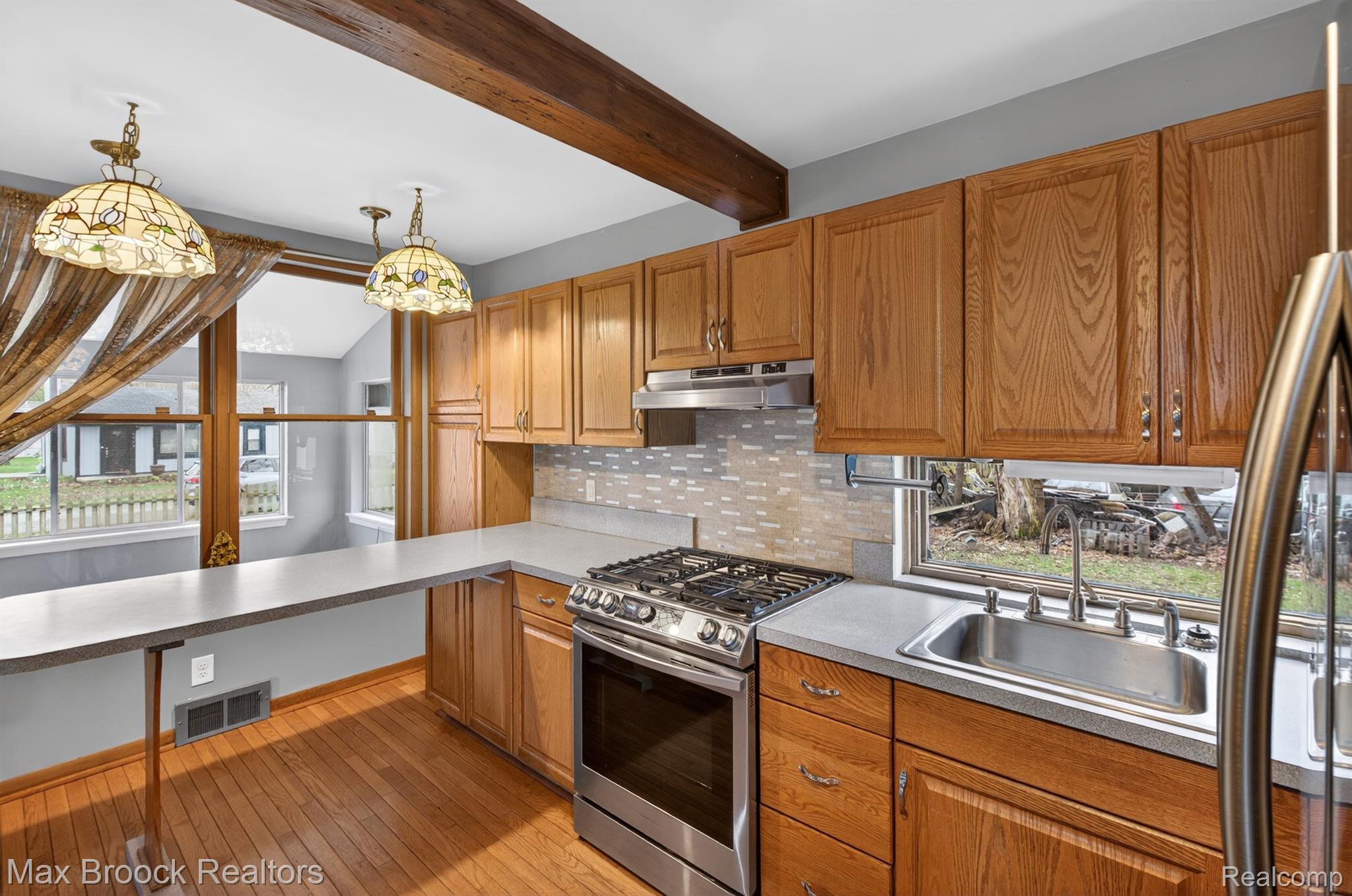 9024 Mandon Road White Lake, MI 48386 - Photo 15 of 39 Kitchen with stainless steel appliances, wood finish cabinetry, tasteful backsplash, light wood-type flooring, and light countertops