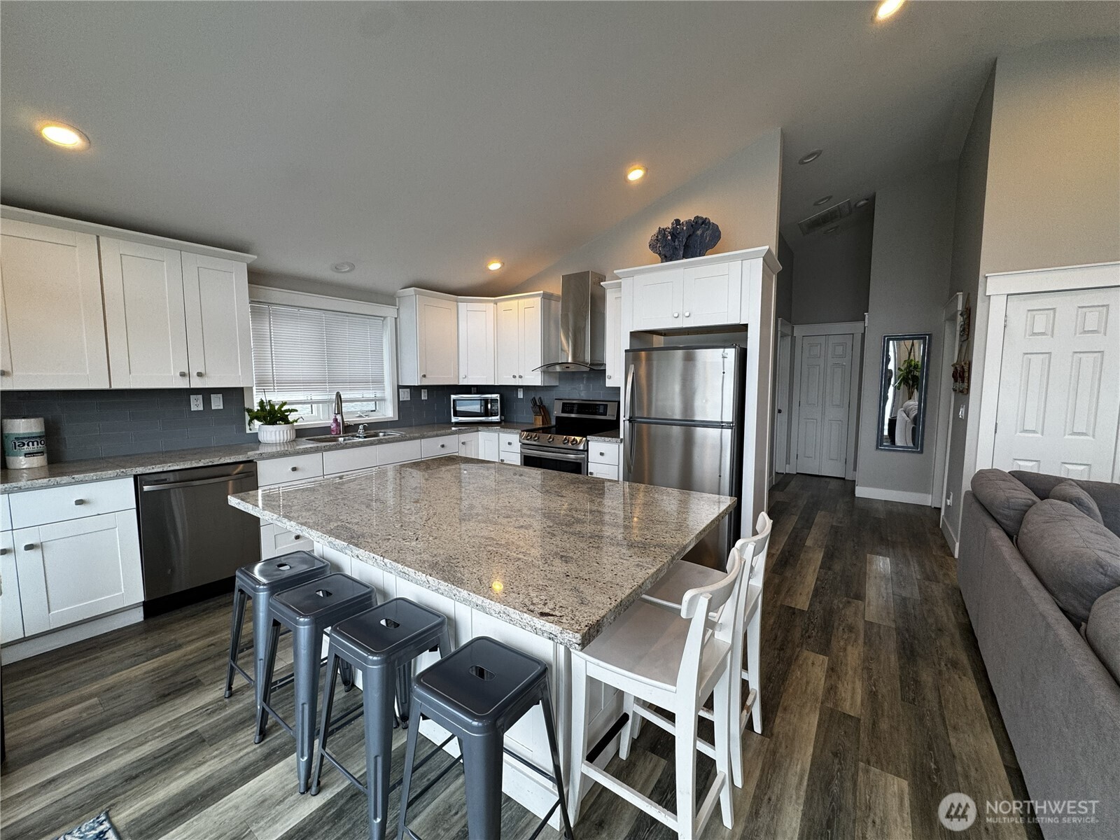 7360 East Grapeview Loop Road Allyn, WA 98524 - Photo 8 of 19 a kitchen with granite countertop a refrigerator a stove a sink a dining table and chairs with wooden floor