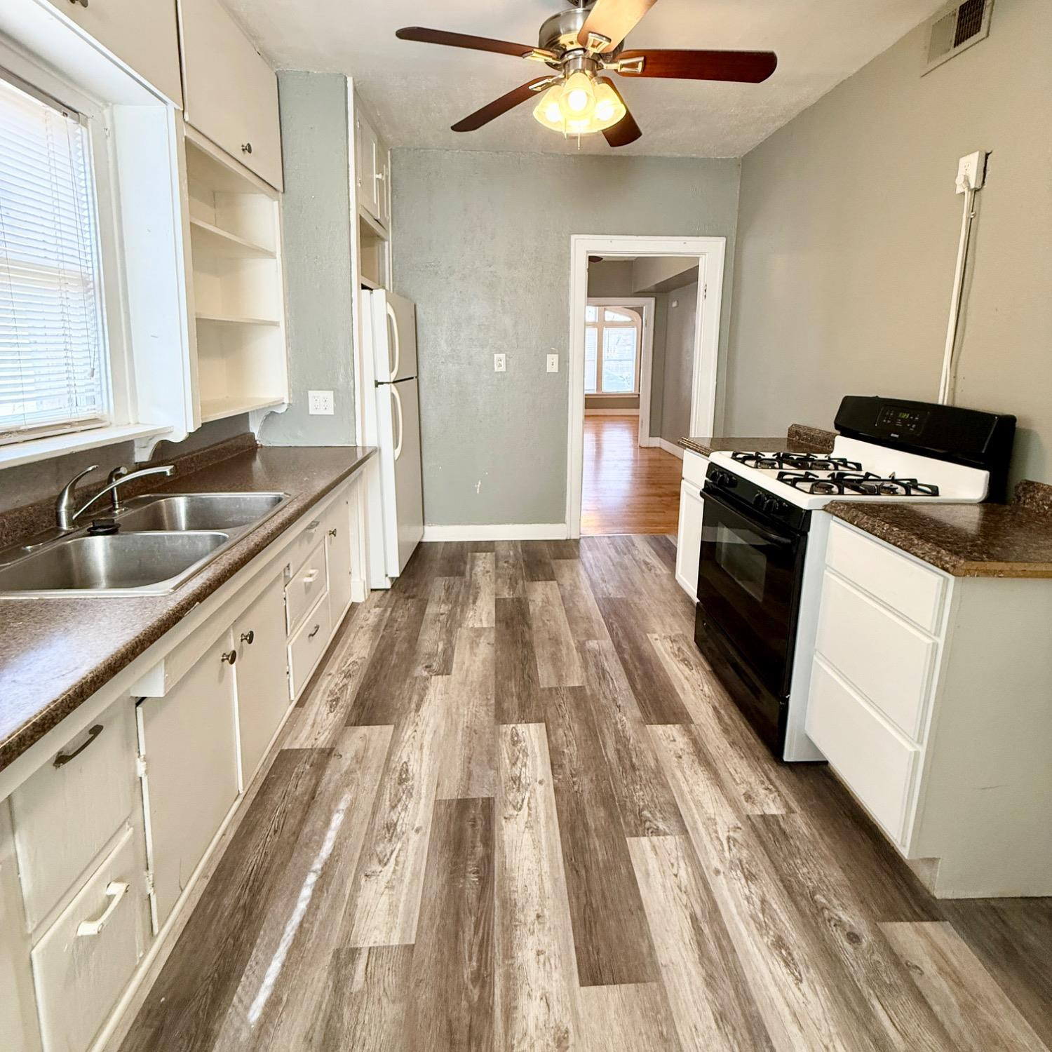 2105 14th Street, Unit 1 Lubbock, TX 79401 - Photo 9 of 11 a kitchen with granite countertop a sink appliances wooden floor and cabinets