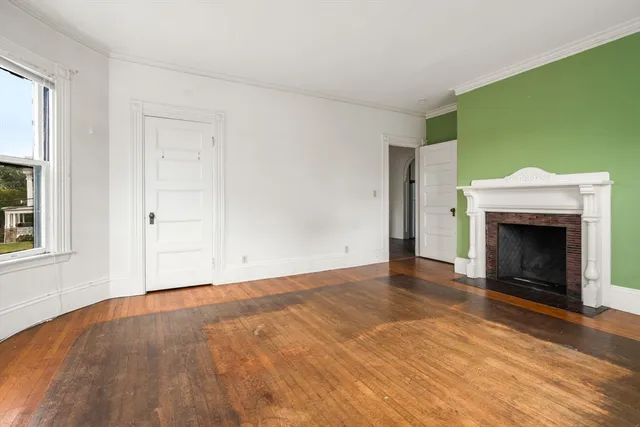 a view of empty room with a fireplace and wooden floor