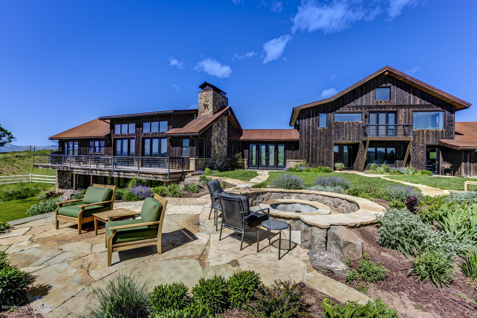 1003 Cattle Creek Ridge Road Carbondale, CO 81623 - Photo 39 of 57 a view of a patio with couches table and chairs under an umbrella with a small yard