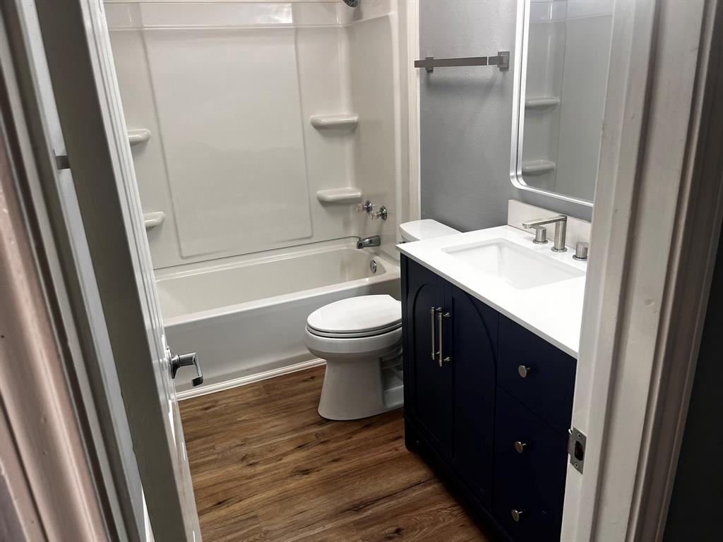 1007 Mack Place Denton, TX 76209 - Photo 33 of 37 Bathroom featuring vanity, dark wood finished floors, and shower combination