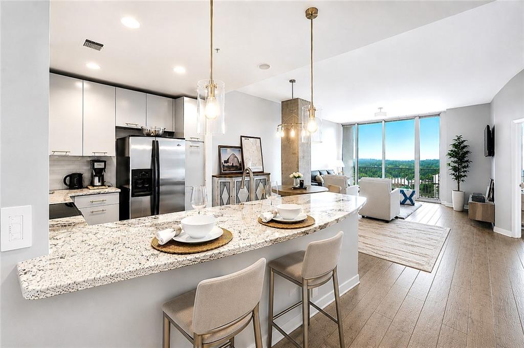 3300 Windy Ridge Parkway Southeast, Unit 1112 Atlanta, GA 30339 - Photo 5 of 43 a kitchen with stainless steel appliances kitchen island granite countertop a refrigerator a sink dishwasher a dining table and chairs with wooden floor