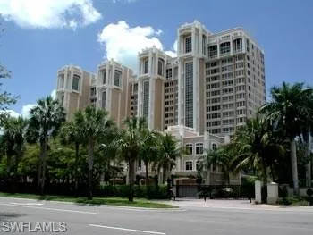 a front view of multi story residential apartment building with yard and parking space