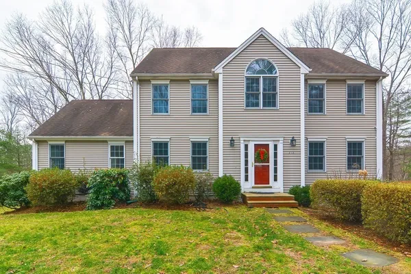 a front view of a house with a yard and trees