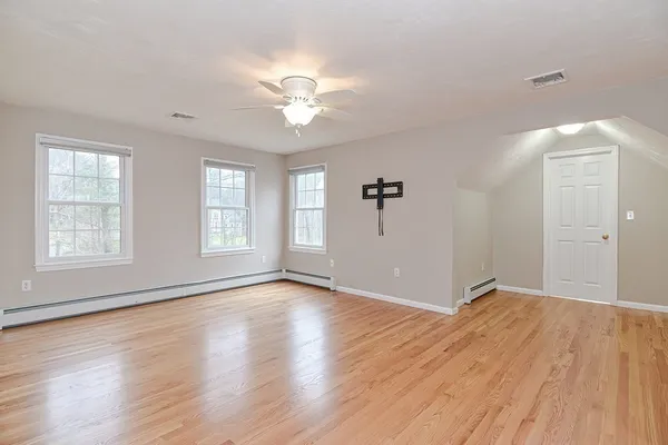 an empty room with wooden floor fan and windows