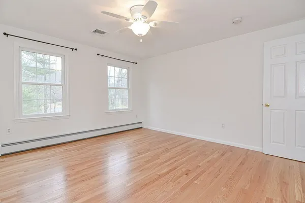 a view of an empty room with wooden floor and a window