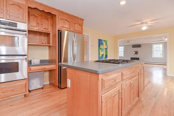 a kitchen with stainless steel appliances granite countertop a stove a sink dishwasher and a refrigerator with wooden floor