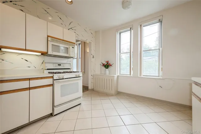 a kitchen with white cabinets appliances and a window