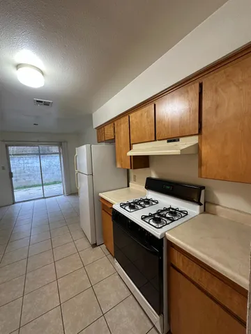 a kitchen with granite countertop a stove a sink dishwasher and a refrigerator