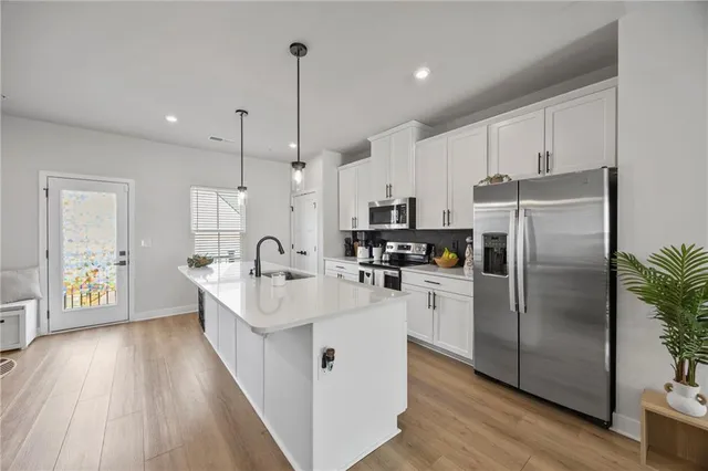 a kitchen with stainless steel appliances granite countertop a refrigerator a sink dishwasher a oven with white cabinets and wooden floor