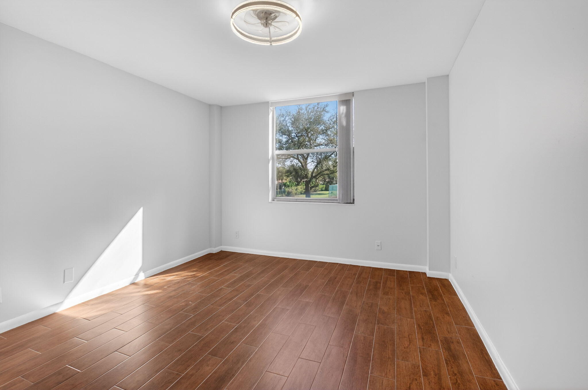 5260 Northwest 2nd Avenue, Unit 206 Boca Raton, FL 33487 - Photo 19 of 36 an empty room with wooden floor and windows