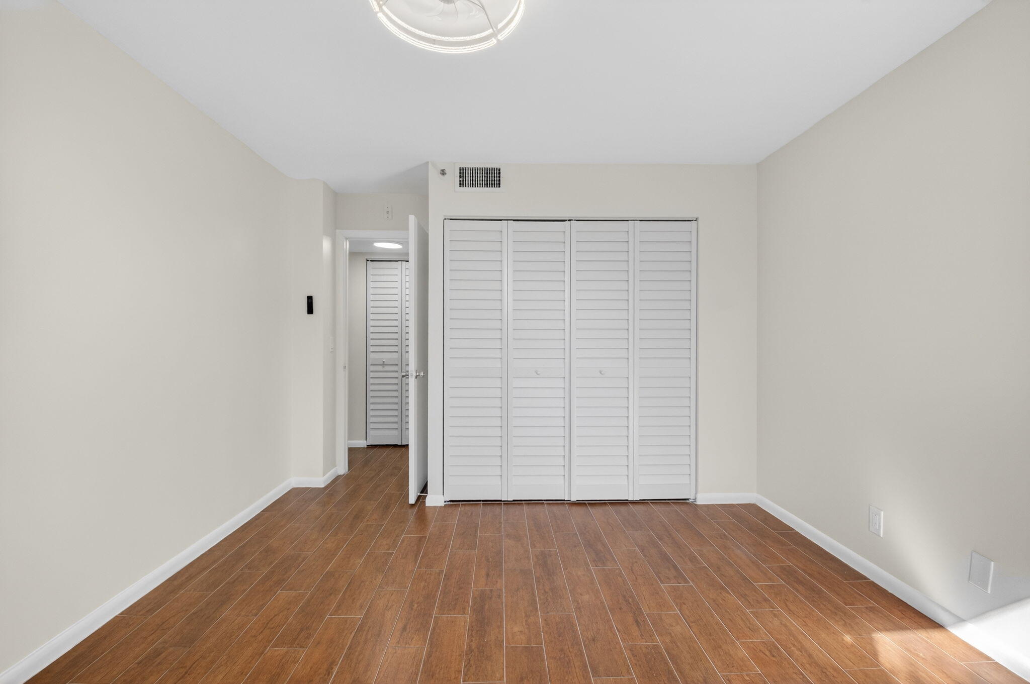 5260 Northwest 2nd Avenue, Unit 206 Boca Raton, FL 33487 - Photo 20 of 36 an empty room with wooden floor and windows