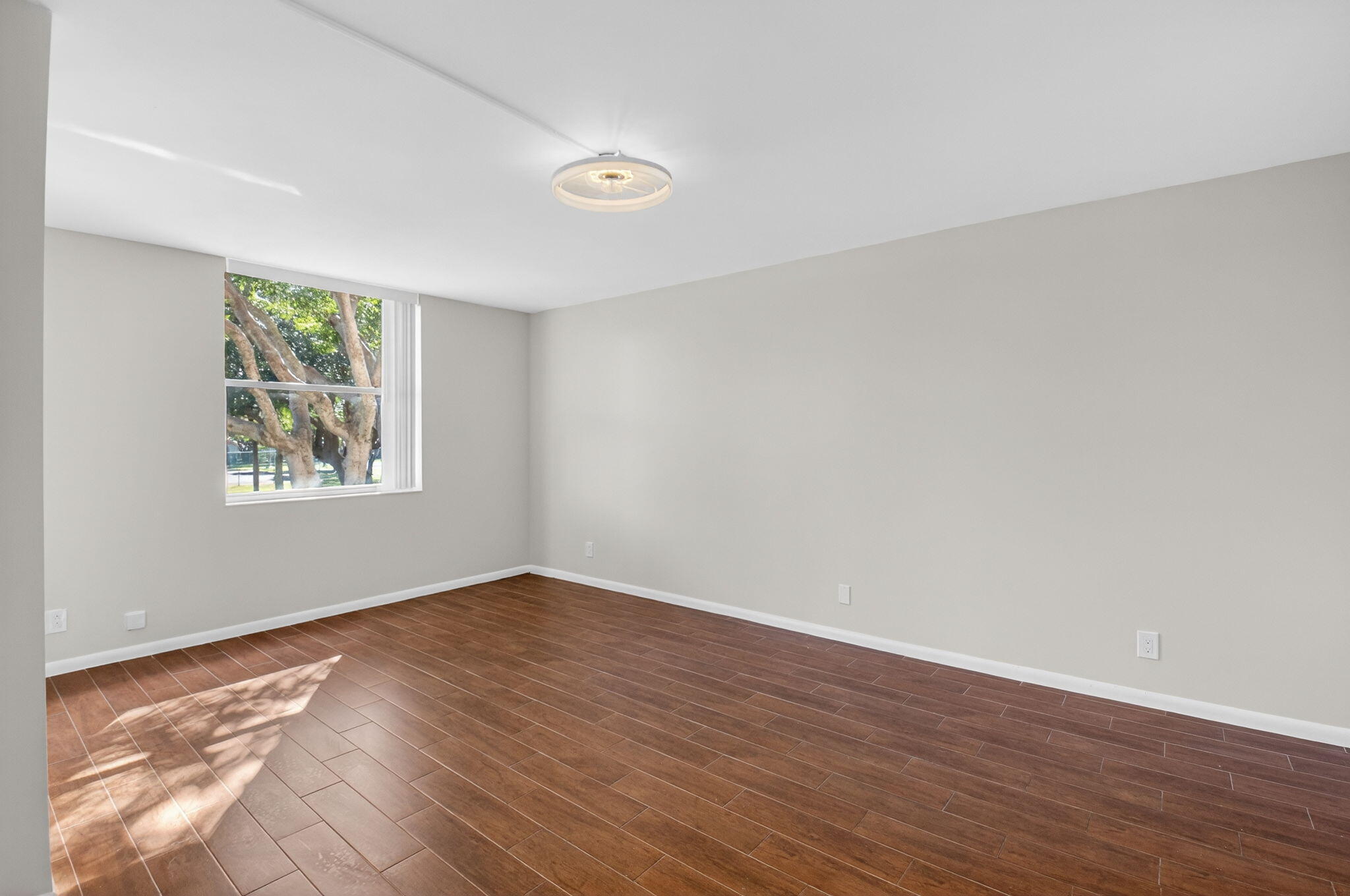 5260 Northwest 2nd Avenue, Unit 206 Boca Raton, FL 33487 - Photo 21 of 36 a view of an empty room with wooden floor and a window