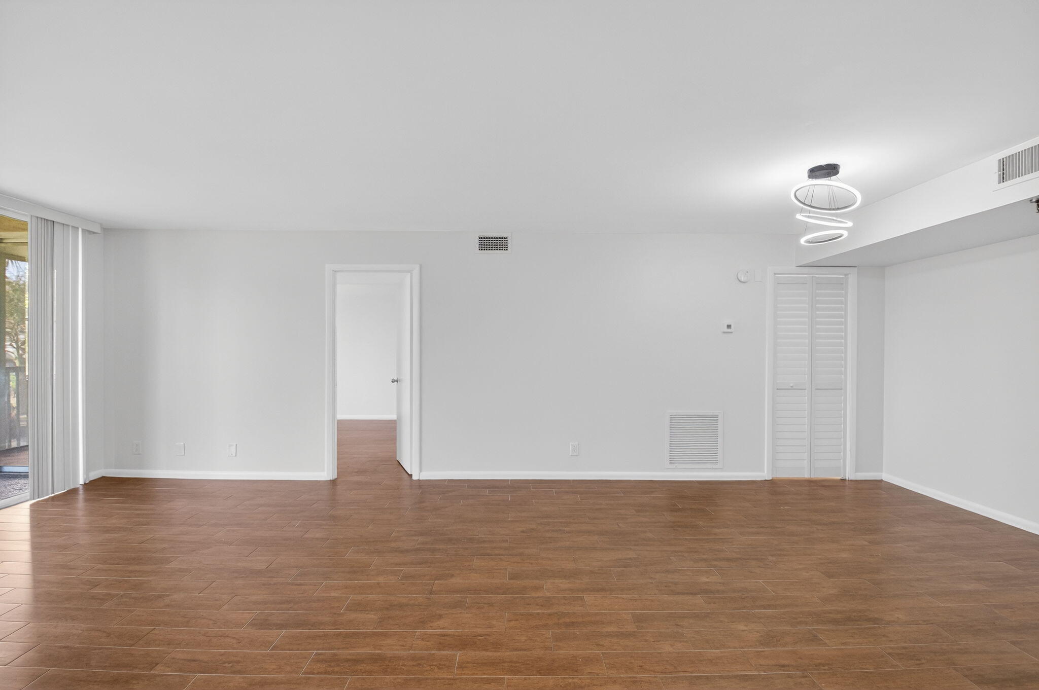 5260 Northwest 2nd Avenue, Unit 206 Boca Raton, FL 33487 - Photo 6 of 36 a view of an empty room with wooden floor and a window