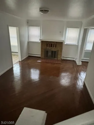 a view of empty room with wooden floor and fireplace