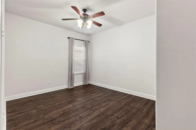 an empty room with wooden floor and a ceiling fan