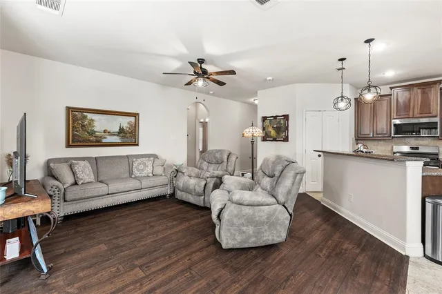 a living room with furniture kitchen view and a wooden floor