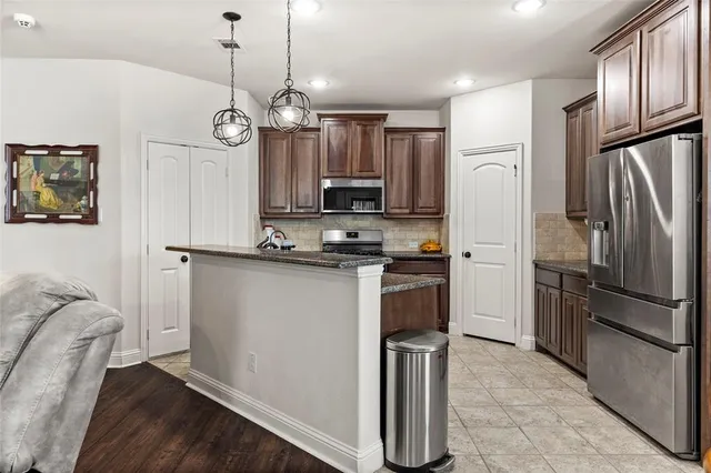 a kitchen with kitchen island a counter space a refrigerator and a sink