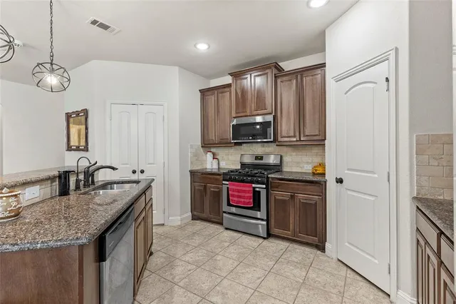 a kitchen with granite countertop a sink stainless steel appliances and cabinets