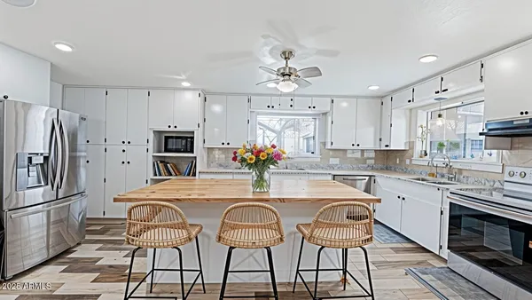 a kitchen with stainless steel appliances a dining table chairs refrigerator and microwave