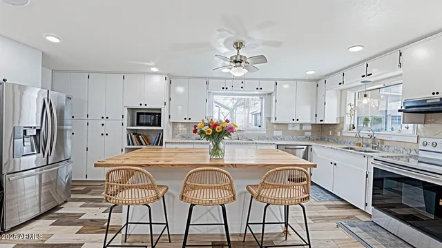 a kitchen with stainless steel appliances a dining table chairs refrigerator and microwave