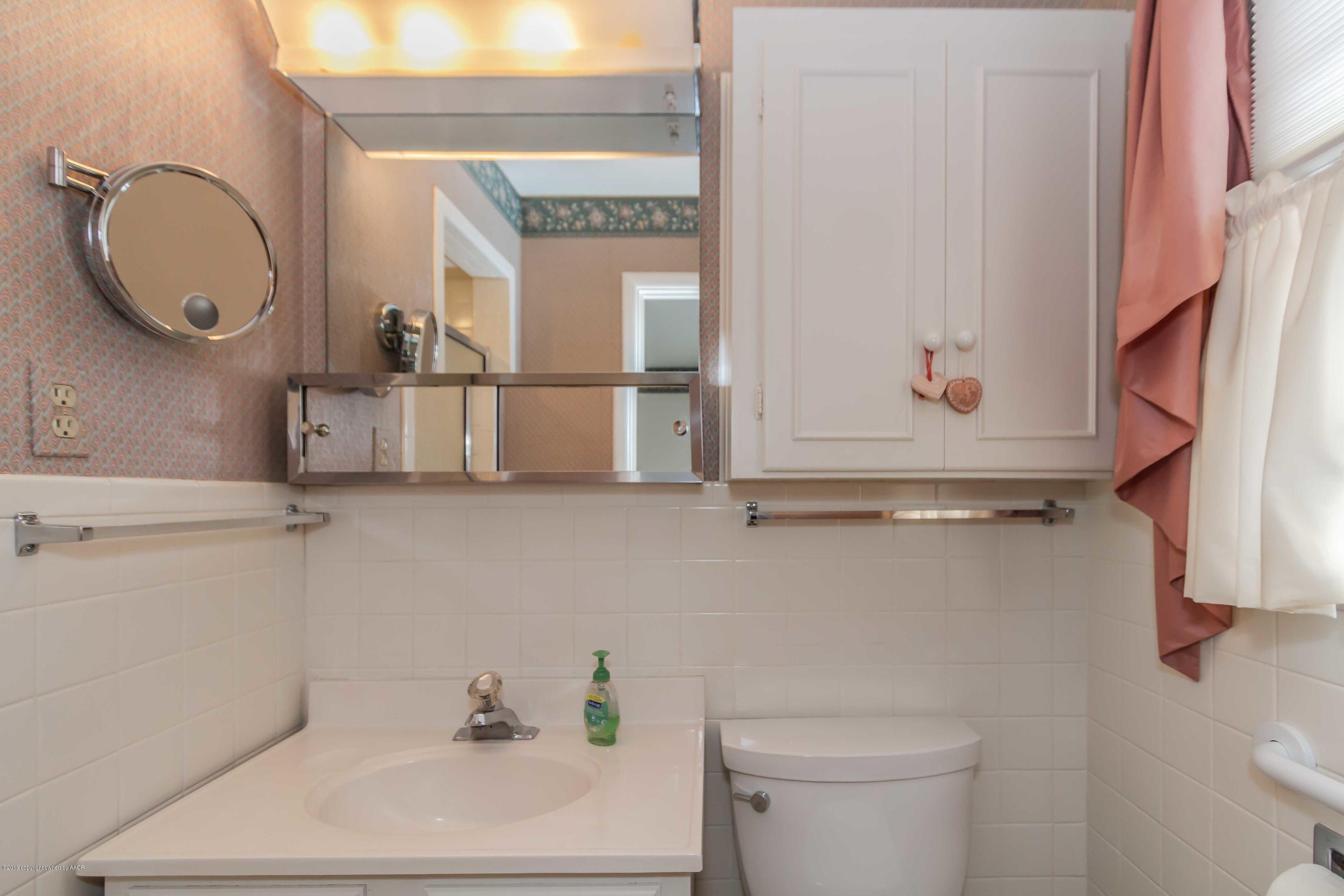 3228 South Travis Street Amarillo, TX 79109 - Photo 26 of 44 a bathroom with a granite countertop sink a toilet and a mirror