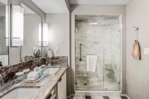 a bathroom with a granite countertop sink a mirror and shower