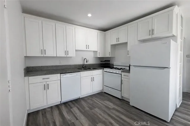 a kitchen with granite countertop white cabinets and refrigerator