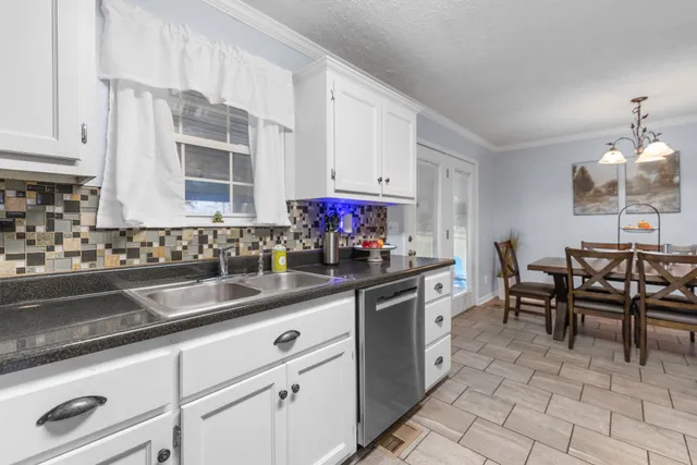 a kitchen with granite countertop a sink chairs and cabinets