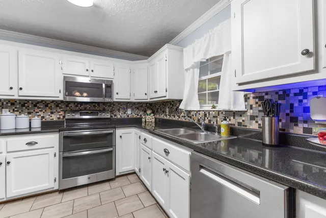 a kitchen with stainless steel appliances granite countertop a sink stove and cabinets