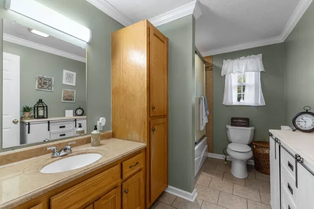 a bathroom with a granite countertop sink toilet and mirror