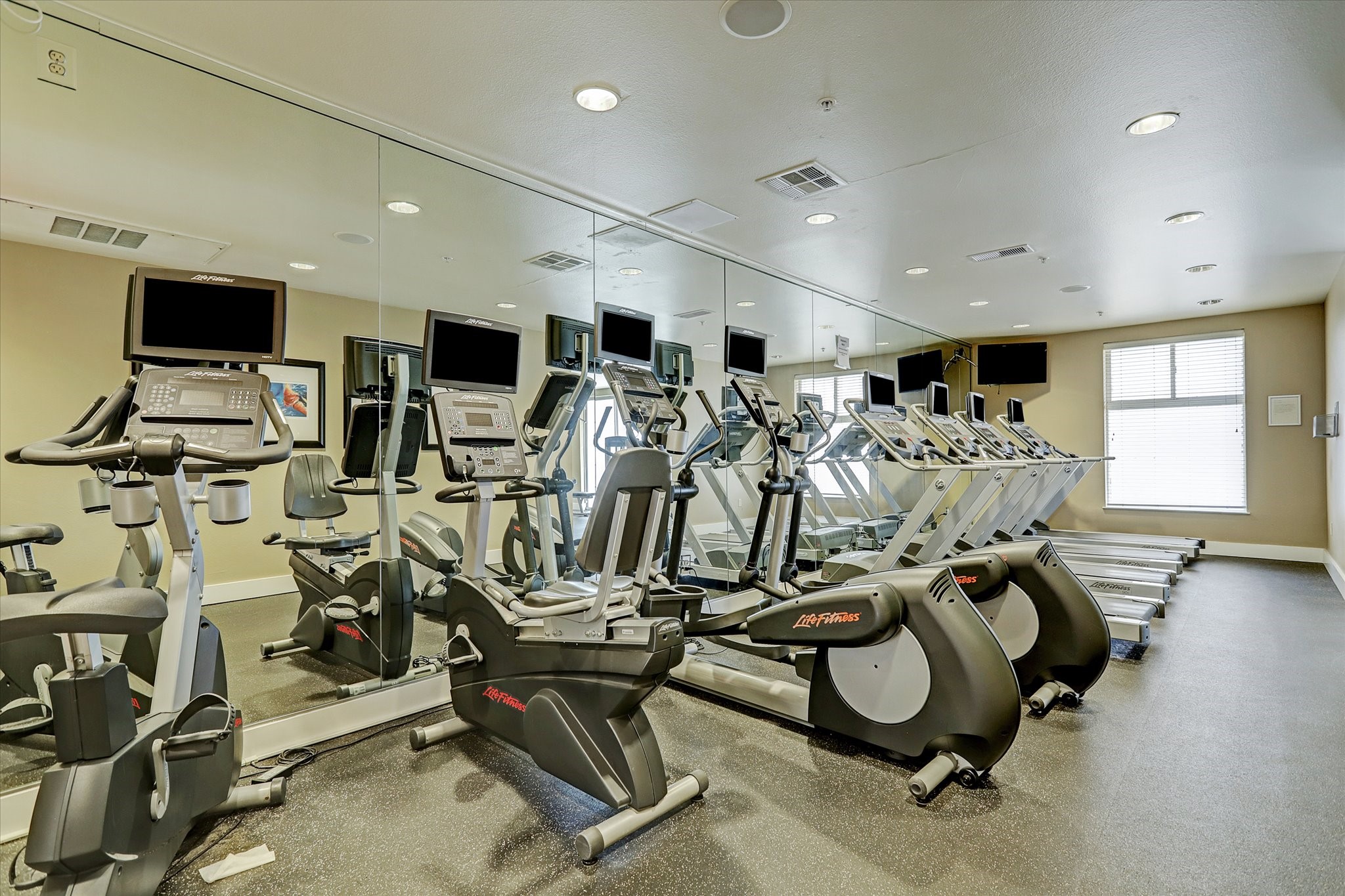 3505 Sage Road, Unit 1104 Houston, TX 77056 - Photo 27 of 31 Residents enjoy access to a fully equipped fitness center designed to support an active lifestyle without leaving the building. The facility features modern cardio equipment including treadmills, stationary bikes, and elliptical machines, all arranged in a spacious and well-lit environment. Wall-length mirrors enhance the open feel while allowing residents to comfortably complete workouts and stay energized just steps from home.